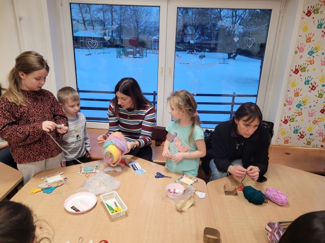 dzieci z rodzicami robia z wloczki serca